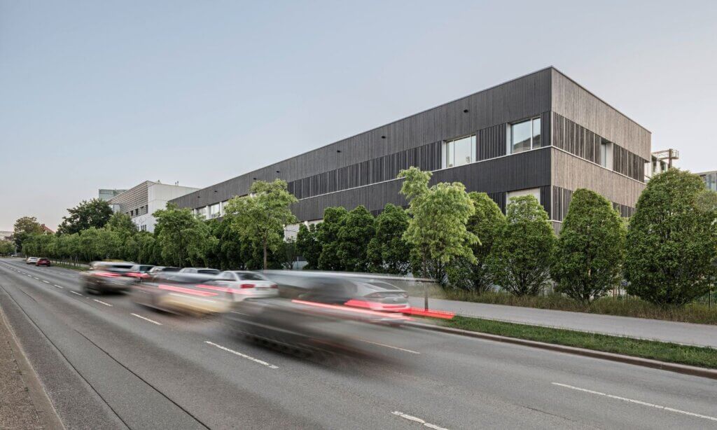 Den Auftakt macht das bereits 2026 fertiggestellte Institut für Labordiagnostik: ein kompakter Baukörper mit karbonisierter Holzfassade, Photovoltaikanlage und Loggien sowie Aufenthaltsbereichen innen wie außen – für das Wohlbefinden der Menschen vor Ort. 