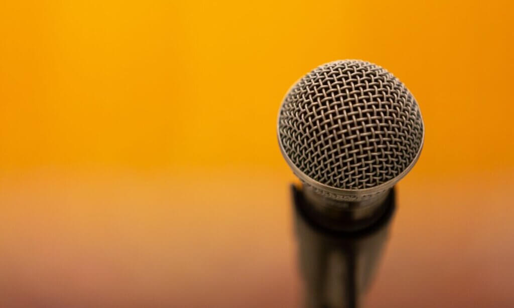 Ein Mikrofon vor gelbem Hintergrund steht sinnbildlich für die Podiumsdiskussion.