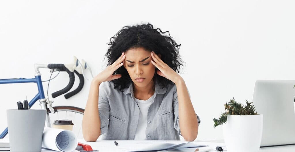 Frau leidet unter Kopfschmerzen – einem typischen Burnout-Symptom.