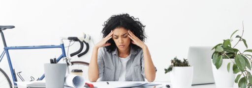 Frau leidet unter Kopfschmerzen – einem typischen Burnout-Symptom.