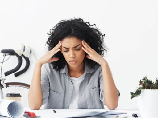 Frau leidet unter Kopfschmerzen – einem typischen Burnout-Symptom.