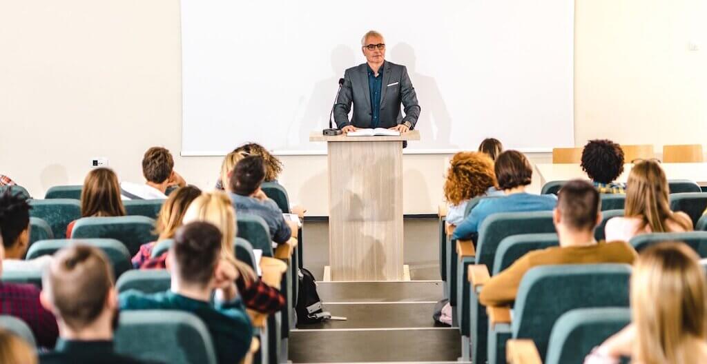 Eine Gruppe TherapeutInnen blickt auf einen Vortragenden auf einem Podium.