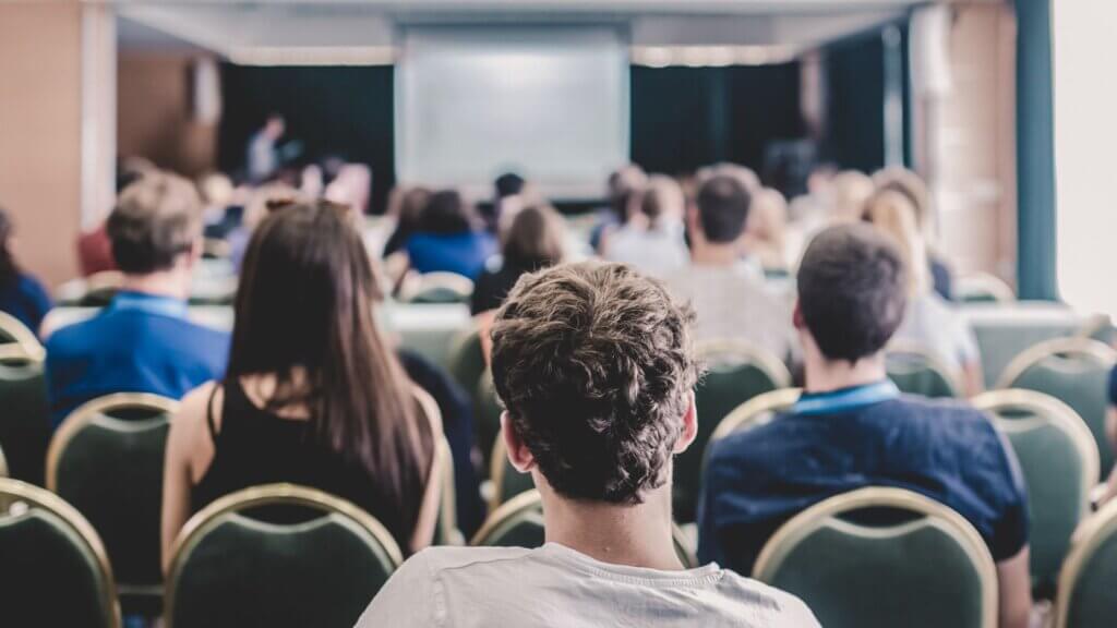 Menschen in einem Saal lauschen einem spannenden Vortrag.