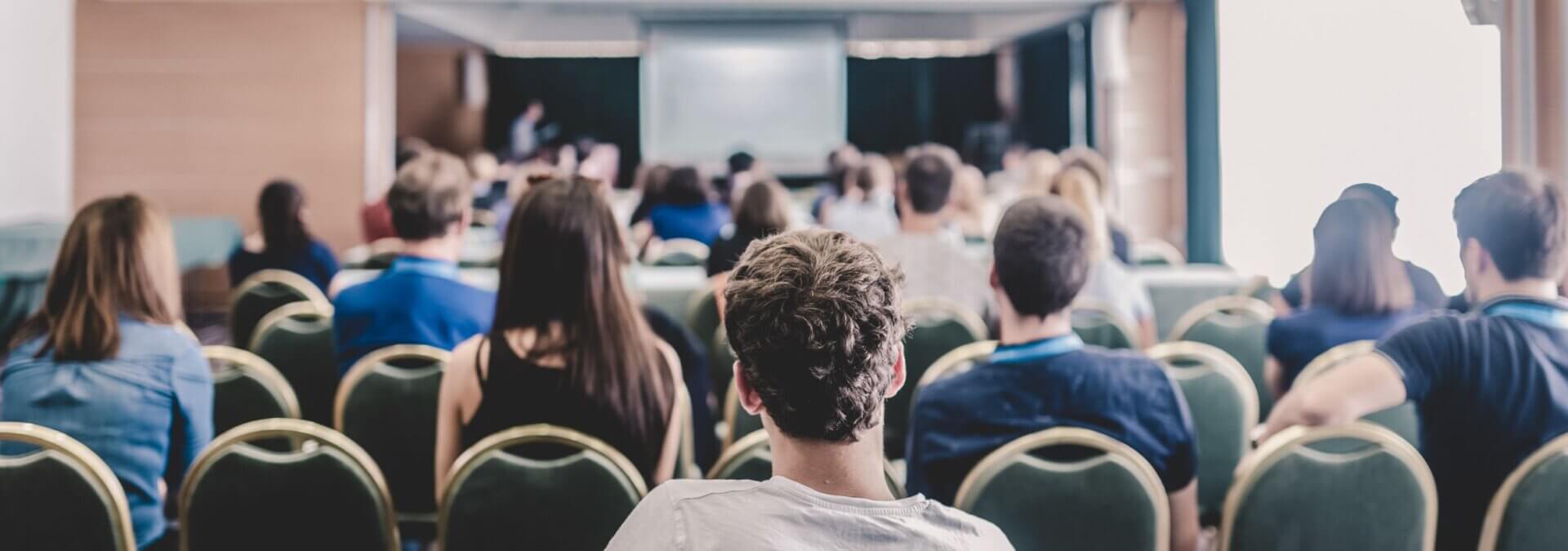 Menschen in einem Saal lauschen einem spannenden Vortrag.