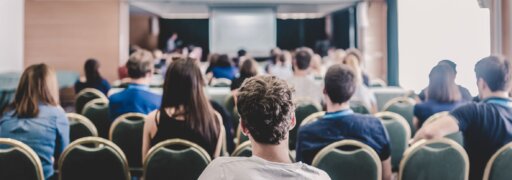 Menschen in einem Saal lauschen einem spannenden Vortrag.