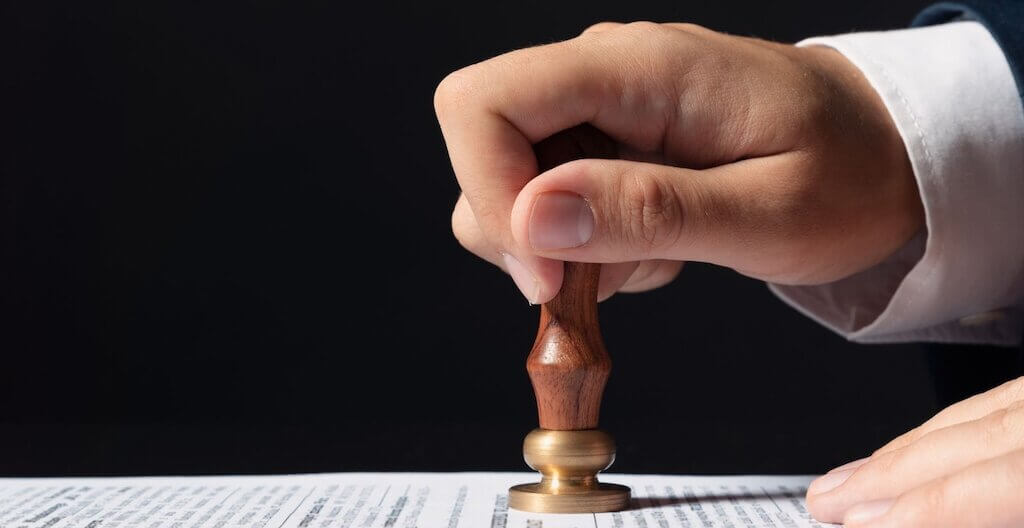 Ein Mann drückt einen Stempel auf ein Papier – ein Sinnbild für gesetzliche Reformen, die 2026 bevorstehen.