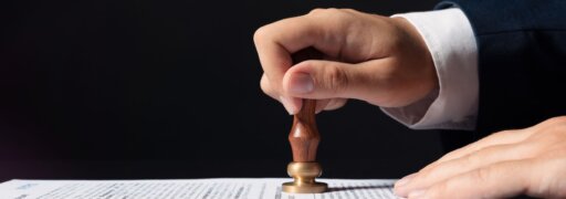 Ein Mann drückt einen Stempel auf ein Papier – ein Sinnbild für gesetzliche Reformen, die 2026 bevorstehen.