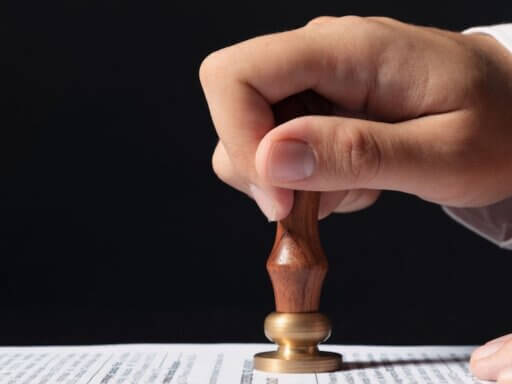 Ein Mann drückt einen Stempel auf ein Papier – ein Sinnbild für gesetzliche Reformen, die 2026 bevorstehen.