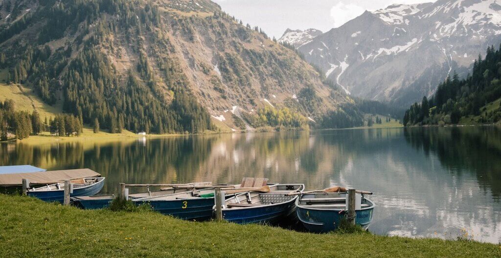 Eine Berglandschaft und ein See mit Booten im Allgäu.