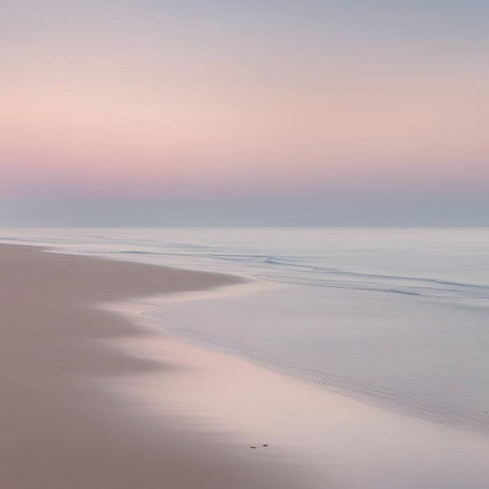 Ein ruhiger Strand in sanftes Sonnenlicht getaucht steht sinnbildlich für Ruhe und Erholung.