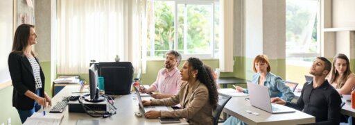 Eine Vortragende erzählt einer Gruppe von sechs Personen mehr zu einem Gesundheitsthema.