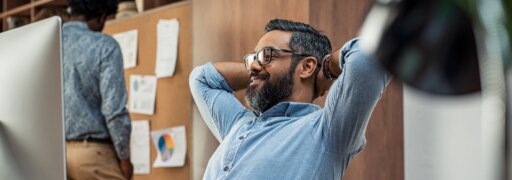 Ein Mann lehnt sich an seinem Arbeitsplatz zufrieden zurück – er hat durch Energiemanagement einen besseren Workflow und ausreichend Pausen erzielt.